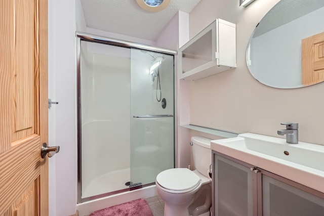 bathroom with tile patterned floors, vanity, a textured ceiling, a shower with door, and toilet