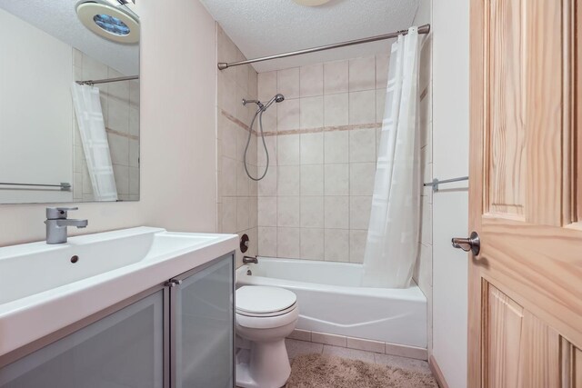 full bathroom with tile patterned floors, a textured ceiling, toilet, vanity, and shower / tub combo