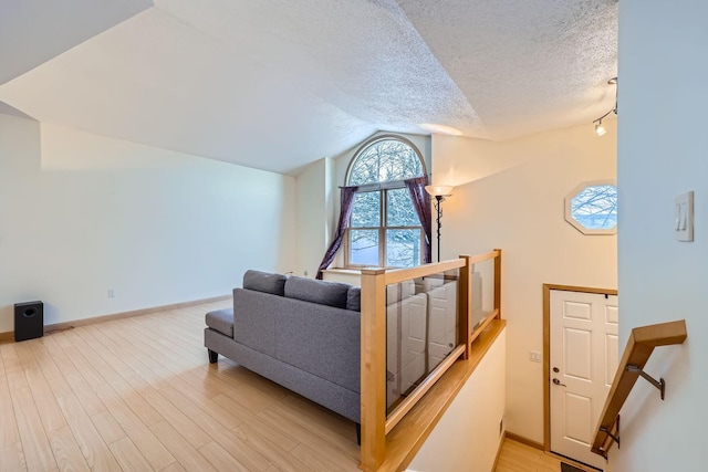 living room with a textured ceiling, light hardwood / wood-style floors, and lofted ceiling