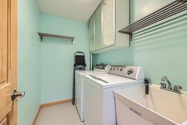 clothes washing area featuring cabinets, a textured ceiling, washer and clothes dryer, and sink