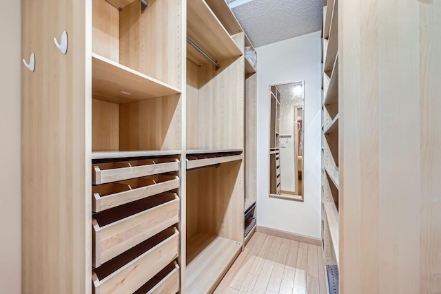 walk in closet with light hardwood / wood-style floors