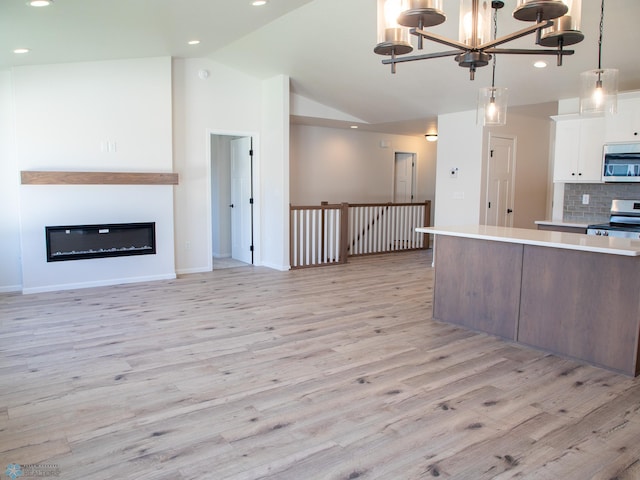 kitchen with decorative backsplash, stainless steel appliances, pendant lighting, white cabinets, and light hardwood / wood-style floors