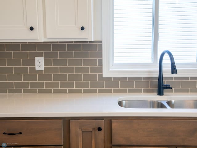 interior details featuring white cabinets, sink, and tasteful backsplash