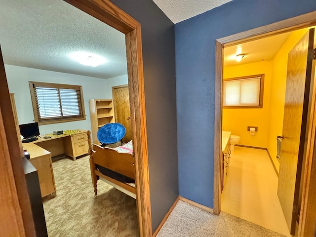 hall featuring light colored carpet and a textured ceiling