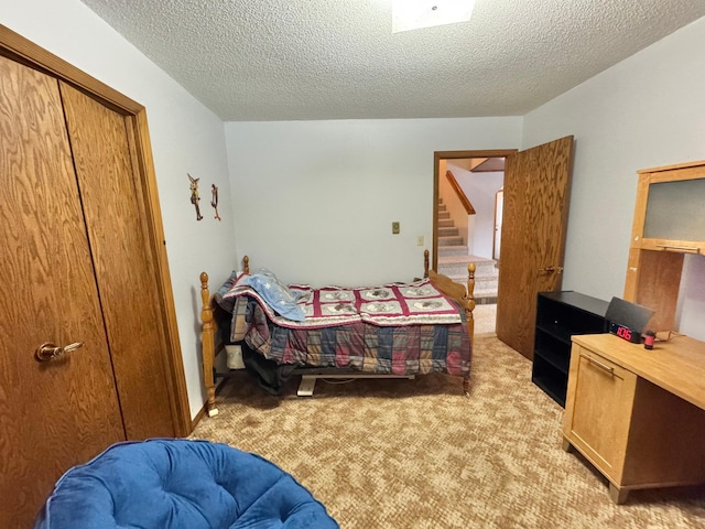 bedroom featuring light carpet, a textured ceiling, and a closet