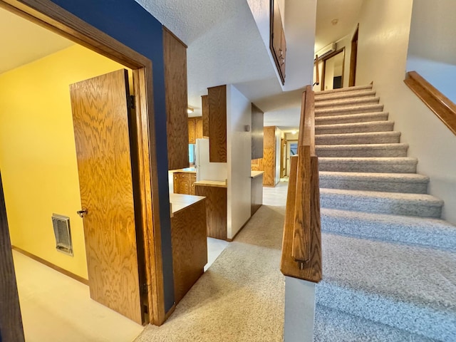 stairs featuring carpet and a textured ceiling