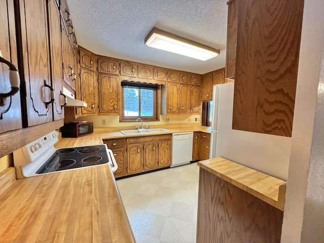 kitchen with kitchen peninsula, a textured ceiling, white appliances, and sink