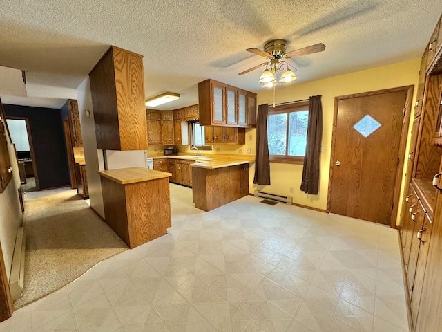 kitchen featuring kitchen peninsula, ceiling fan, baseboard heating, sink, and a kitchen island