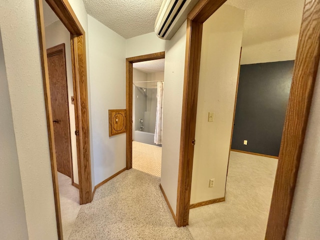 corridor with a textured ceiling and light colored carpet