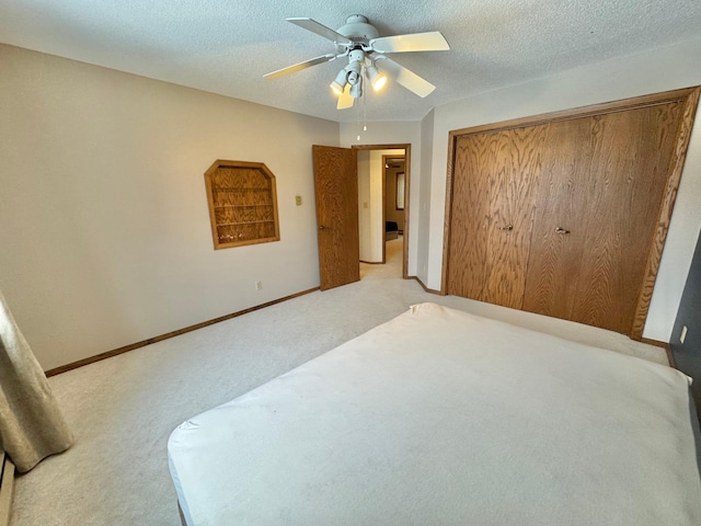 carpeted bedroom with a textured ceiling, a closet, and ceiling fan