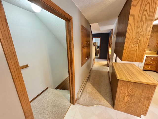 corridor with light carpet, lofted ceiling, a textured ceiling, and a baseboard heating unit