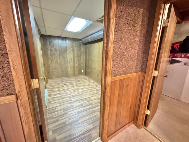 interior space with wood walls, light hardwood / wood-style flooring, and a drop ceiling