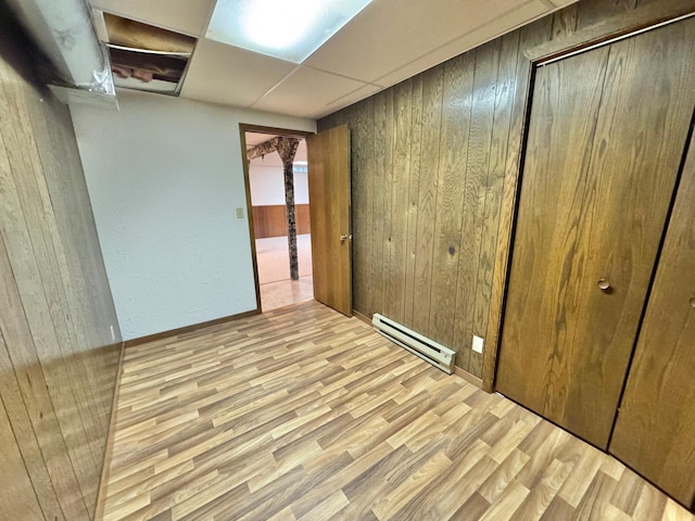 spare room featuring wooden walls, light hardwood / wood-style flooring, and a baseboard heating unit