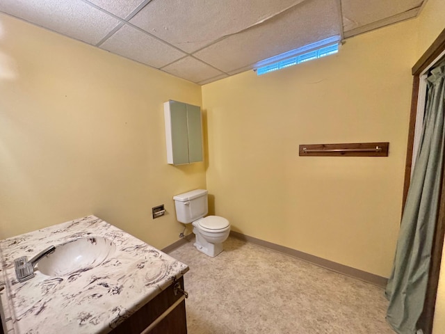 bathroom with vanity, toilet, and a drop ceiling