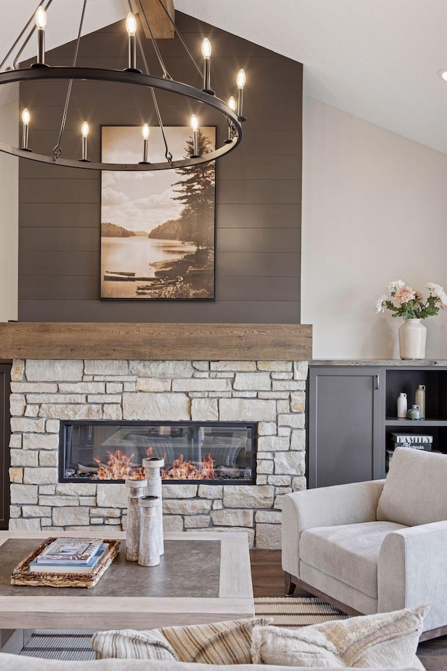 living area featuring vaulted ceiling and a stone fireplace