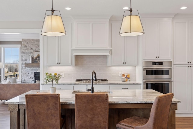 kitchen with double oven, tasteful backsplash, and white cabinets