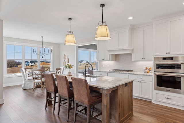 kitchen featuring dark wood-style floors, appliances with stainless steel finishes, a sink, white cabinetry, and backsplash