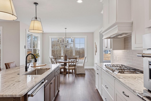 kitchen with tasteful backsplash, dishwasher, custom exhaust hood, stainless steel gas stovetop, and a sink