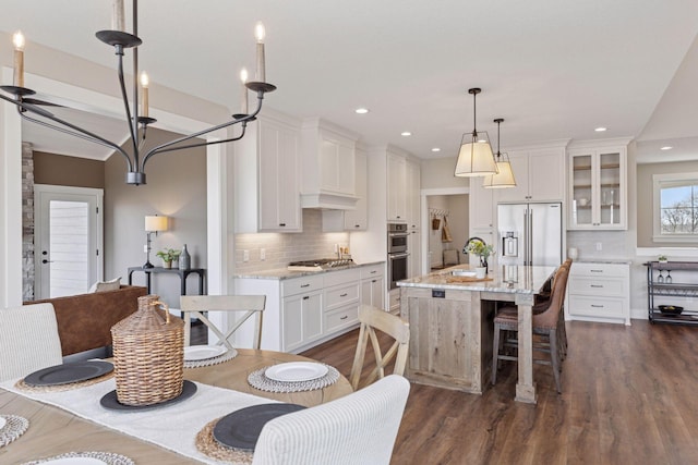 kitchen featuring white cabinets, dark wood finished floors, an island with sink, glass insert cabinets, and stainless steel appliances