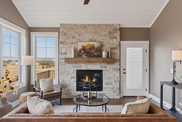 living area with a fireplace, baseboards, vaulted ceiling, and wood finished floors