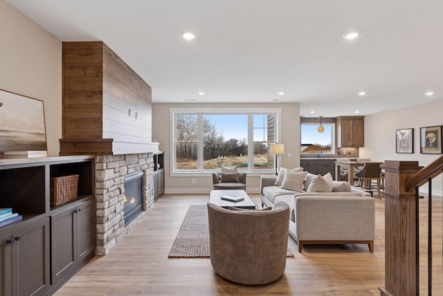 living room with light wood-style floors, recessed lighting, a fireplace, and baseboards