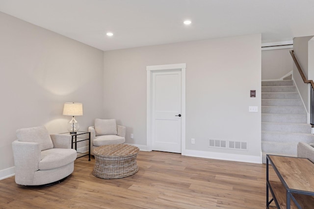 living area with recessed lighting, wood finished floors, visible vents, and stairs