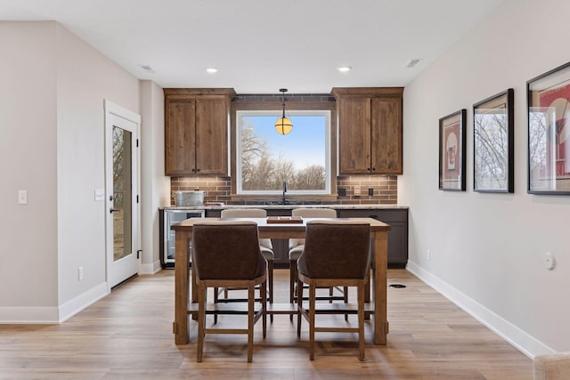 kitchen with beverage cooler, tasteful backsplash, light wood-type flooring, and baseboards