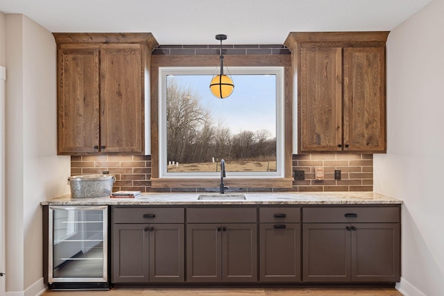 kitchen with light stone counters, wine cooler, a sink, and gray cabinetry