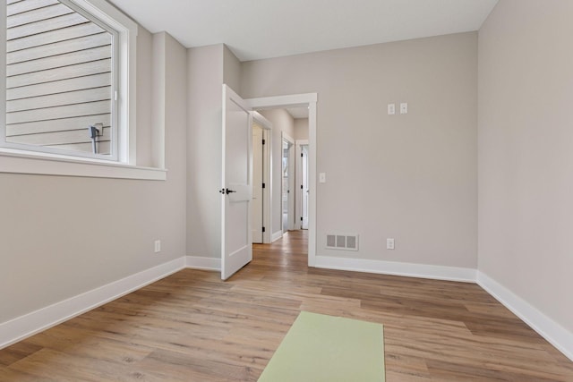 spare room with light wood finished floors, visible vents, and baseboards