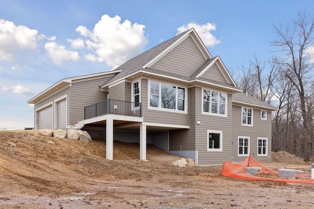 back of house featuring a shingled roof and an attached garage