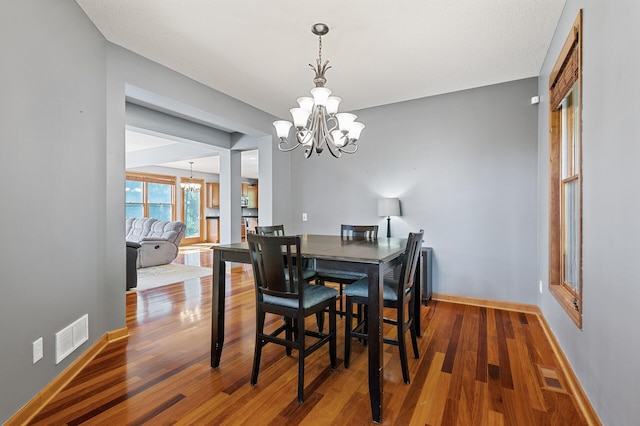 dining space featuring hardwood / wood-style flooring and a chandelier