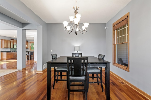 dining space featuring hardwood / wood-style flooring and an inviting chandelier