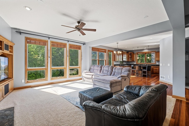 living room featuring hardwood / wood-style floors and ceiling fan with notable chandelier