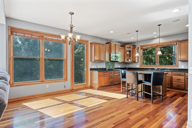 kitchen with sink, a center island, light hardwood / wood-style flooring, decorative light fixtures, and a breakfast bar