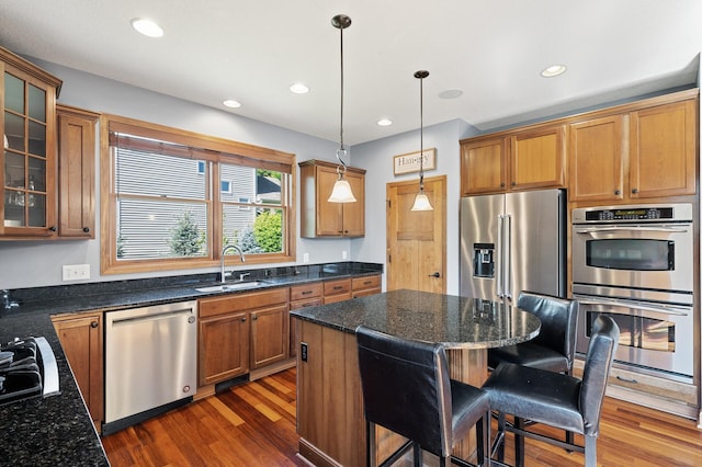 kitchen with a kitchen breakfast bar, stainless steel appliances, sink, pendant lighting, and a center island