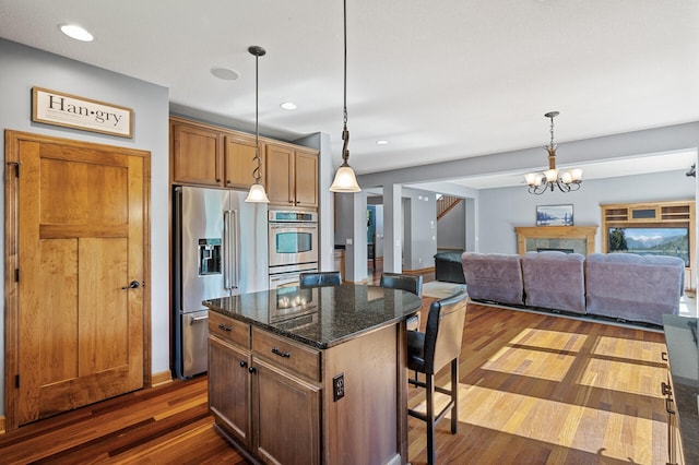 kitchen featuring a center island, dark wood-type flooring, stainless steel appliances, a kitchen breakfast bar, and dark stone counters