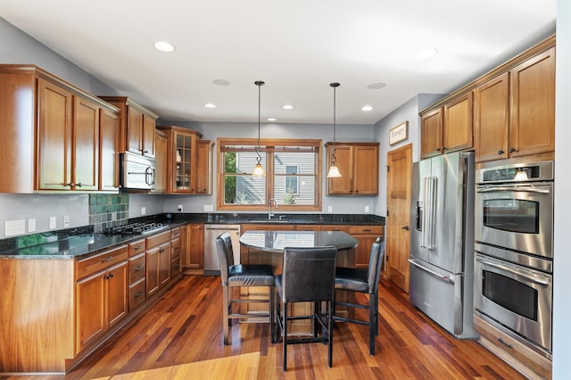 kitchen featuring a kitchen bar, appliances with stainless steel finishes, pendant lighting, a center island, and dark hardwood / wood-style floors