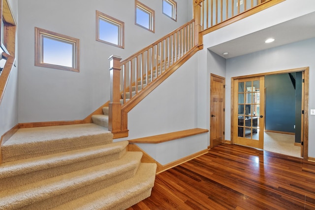 staircase with a towering ceiling and wood-type flooring