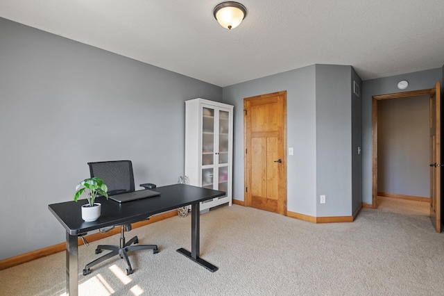 office area with a textured ceiling and light carpet