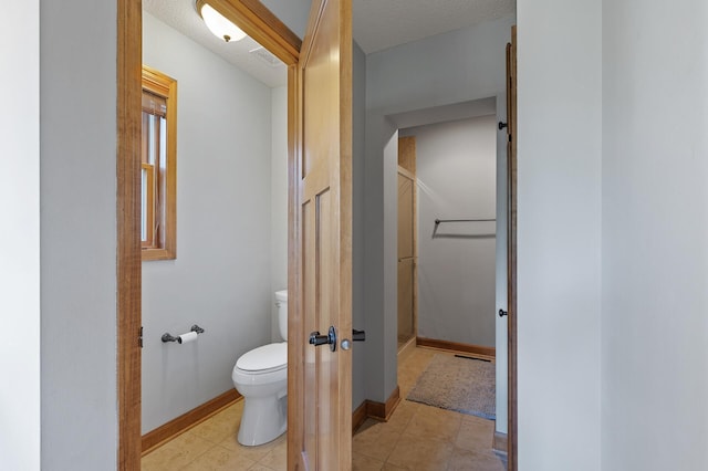 bathroom featuring tile patterned flooring, toilet, and a textured ceiling