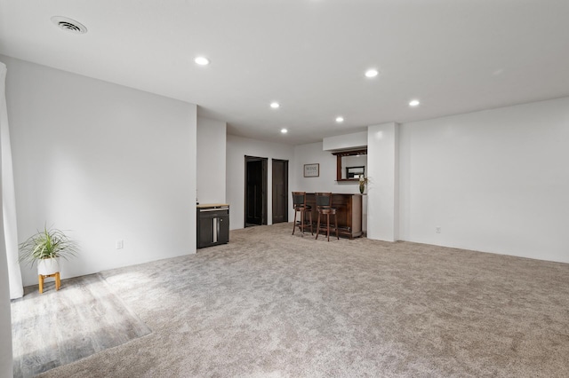 unfurnished living room with carpet and indoor bar