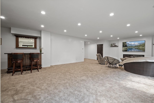 sitting room featuring light colored carpet and bar