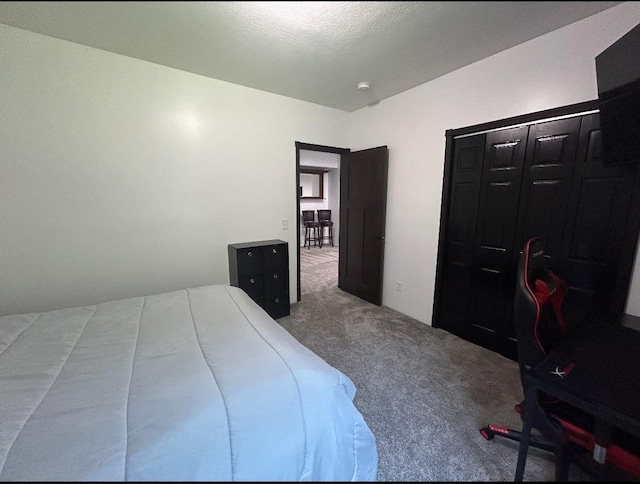 bedroom with a textured ceiling, carpet floors, and a closet