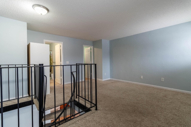 corridor with light colored carpet and a textured ceiling