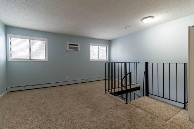 spare room featuring a textured ceiling, a baseboard radiator, a wall unit AC, and light colored carpet