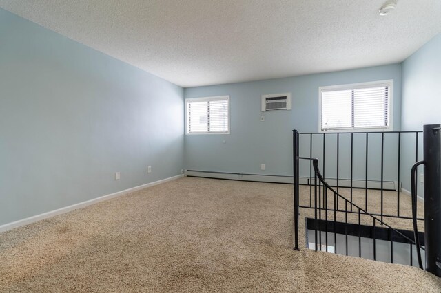 empty room featuring carpet floors, a textured ceiling, and a wall mounted AC