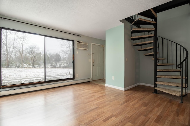 interior space with a wall unit AC, hardwood / wood-style floors, a baseboard radiator, and a textured ceiling