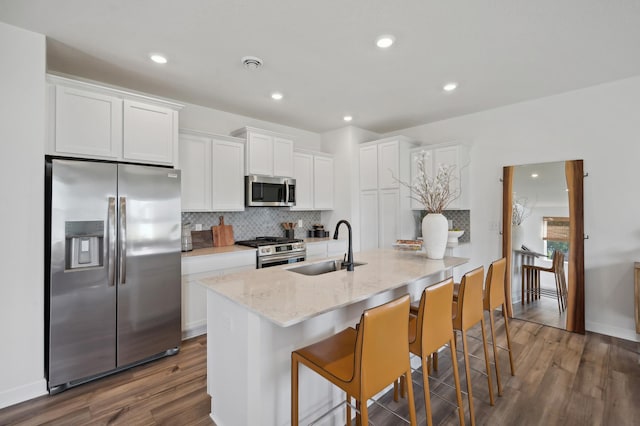 kitchen featuring white cabinetry, sink, stainless steel appliances, a kitchen breakfast bar, and dark hardwood / wood-style flooring