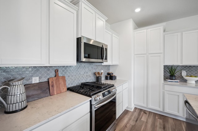 kitchen with decorative backsplash, light stone counters, white cabinetry, and appliances with stainless steel finishes