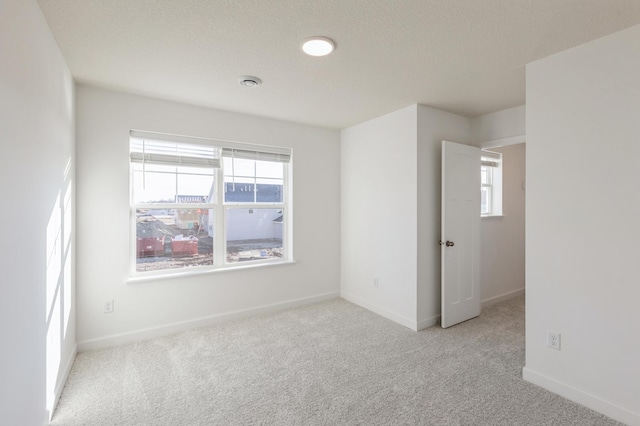 carpeted empty room featuring a wealth of natural light and a textured ceiling